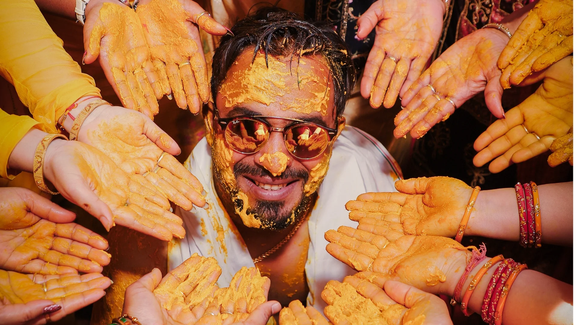 Groom enjoying haldi ceremony surrounded by family captured by Indo Frames