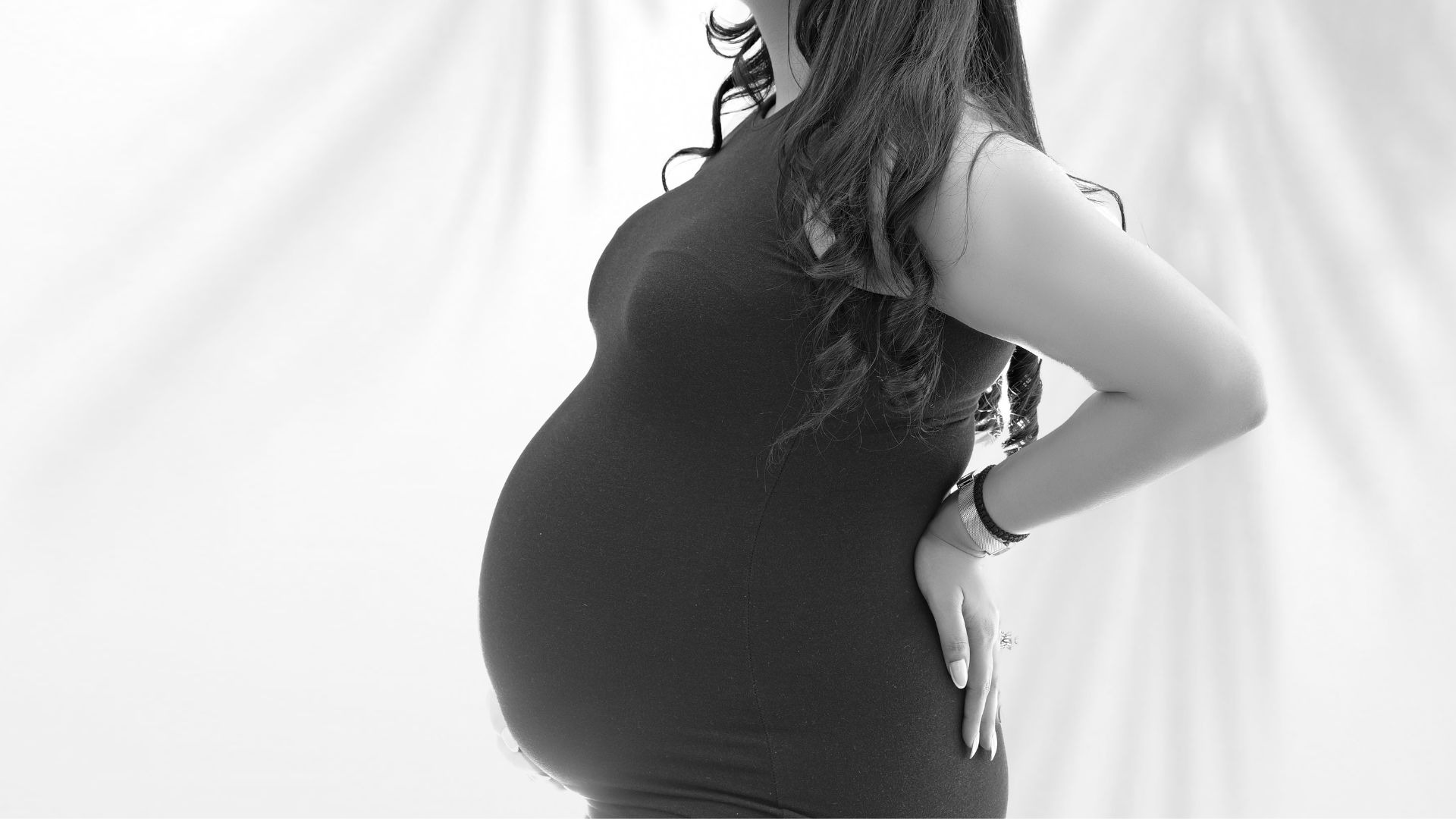 Black and white artistic side profile of pregnant woman showing baby bump — maternity photoshoot by Indo Frames, ideal for Instagram captions